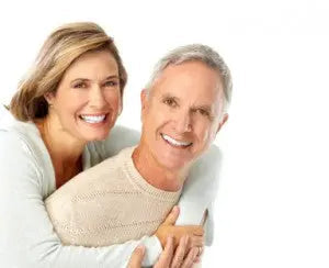 Smiling middle-aged couple embracing with woman standing behind man against a plain white background