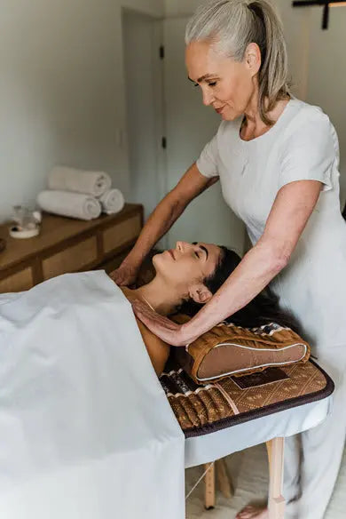 Therapist adjusting a woman on a treatment table with a Biomat under her shoulders in a calm clinic setting