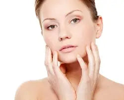 Close-up of a woman touching her face, showing clear glowing skin on a white background