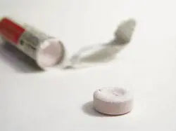 Close-up of Alkal-Life effervescent water purification tablet beside an open tube and foil wrapper on white background