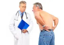 Man clutching his lower back in pain while a doctor in a white coat looks on in a clinic setting